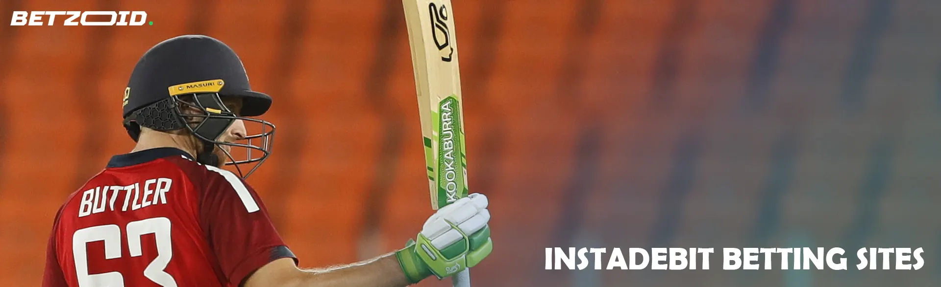 A cricketer is holding a bat while standing on the field.
