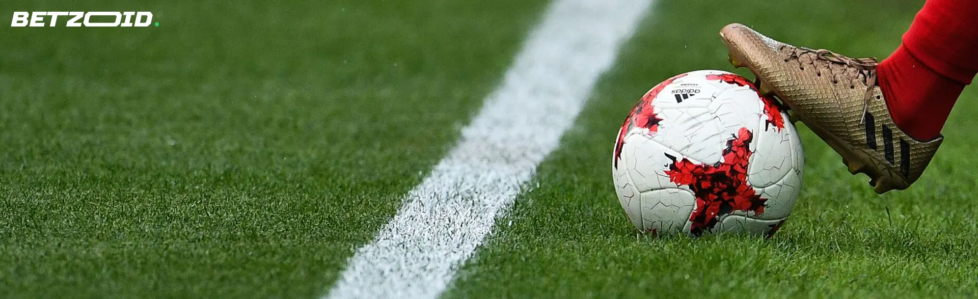 A football player holds the ball on the field line.