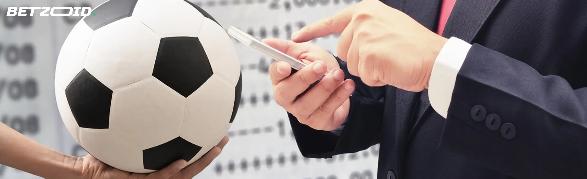 Ein Mann im Anzug hält ein Telefon, daneben liegt ein Fußball.